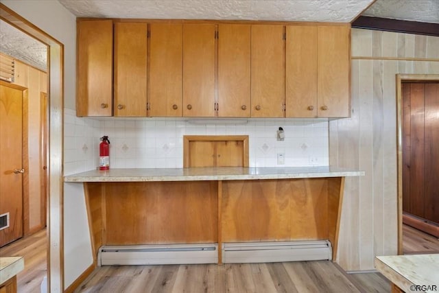 kitchen featuring backsplash, a baseboard radiator, and light hardwood / wood-style floors