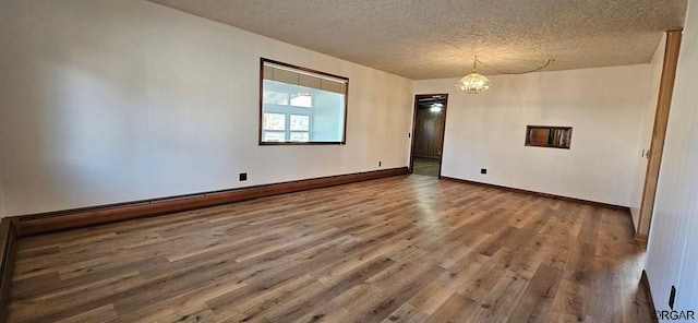 spare room with hardwood / wood-style floors, a textured ceiling, and a notable chandelier