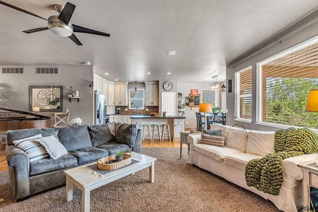 living room with sink, ceiling fan, and light hardwood / wood-style flooring