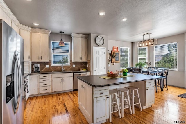 kitchen with appliances with stainless steel finishes, a center island, sink, and hanging light fixtures