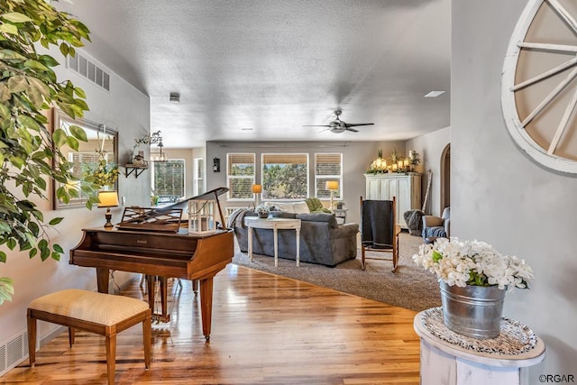 misc room featuring wood-type flooring, a textured ceiling, and ceiling fan