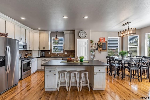 kitchen featuring pendant lighting, sink, a breakfast bar, stainless steel appliances, and a center island