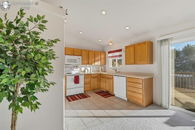 kitchen with sink, white appliances, vaulted ceiling, and light tile patterned flooring