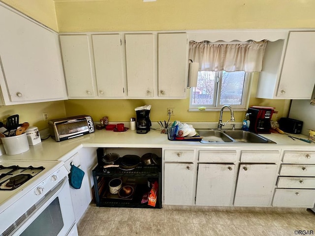 kitchen with white range, sink, and white cabinets