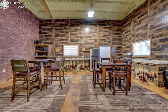 dining room featuring brick wall and a high ceiling