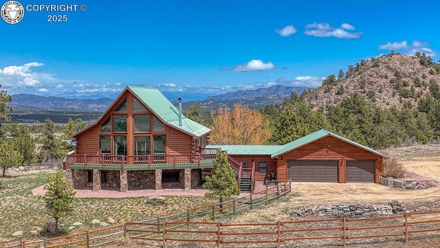exterior space featuring stone siding, log siding, driveway, a deck with mountain view, and fence private yard