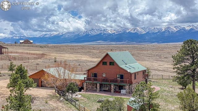 back of property featuring a rural view, a mountain view, fence, and log siding