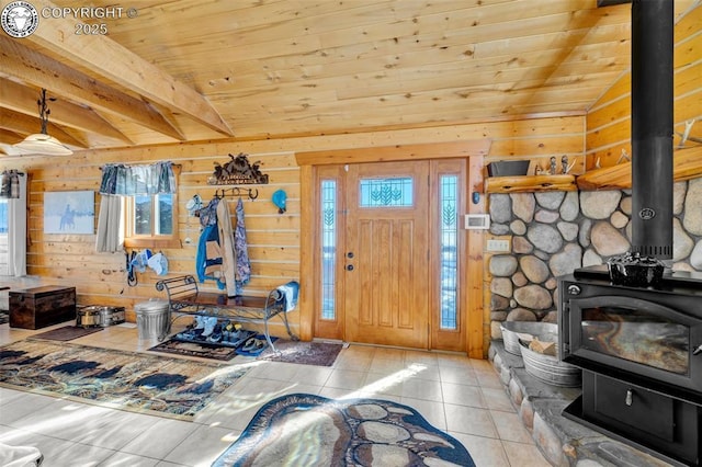 tiled entrance foyer featuring a wealth of natural light, a wood stove, wooden walls, and wood ceiling
