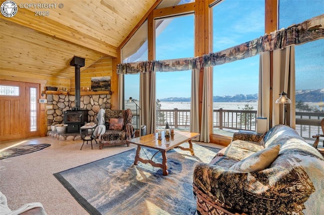 living room with a mountain view, a wood stove, high vaulted ceiling, wooden ceiling, and carpet floors