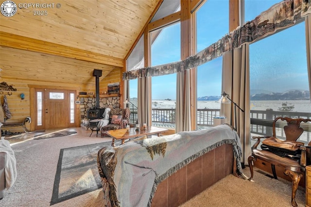 carpeted living room featuring a mountain view, a wood stove, high vaulted ceiling, wooden ceiling, and wooden walls