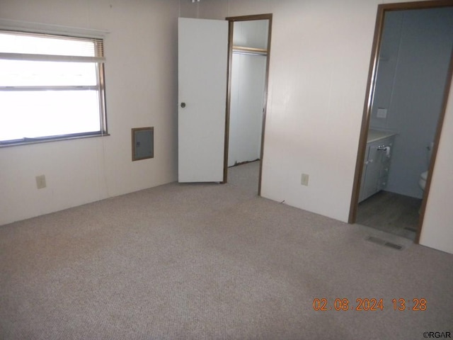 unfurnished bedroom featuring a closet, connected bathroom, and light carpet