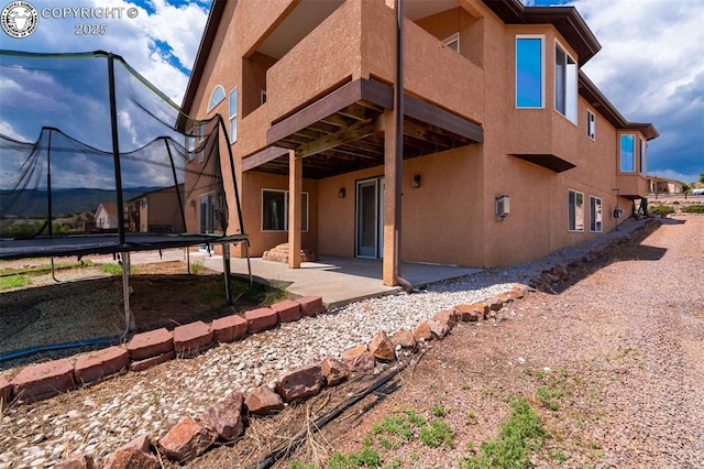 46 Wild Rose Dr, Canon City, CO 81212 - back of house with a trampoline, a patio, and stucco siding