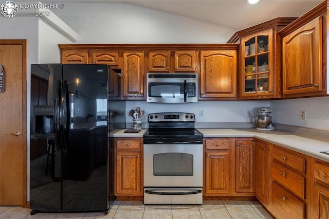 46 Wild Rose Dr, Canon City, CO 81212 - kitchen with stainless steel appliances, vaulted ceiling, light countertops, glass insert cabinets, and brown cabinetry