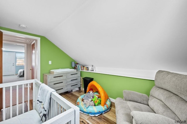 bedroom featuring a crib, lofted ceiling, and hardwood / wood-style floors