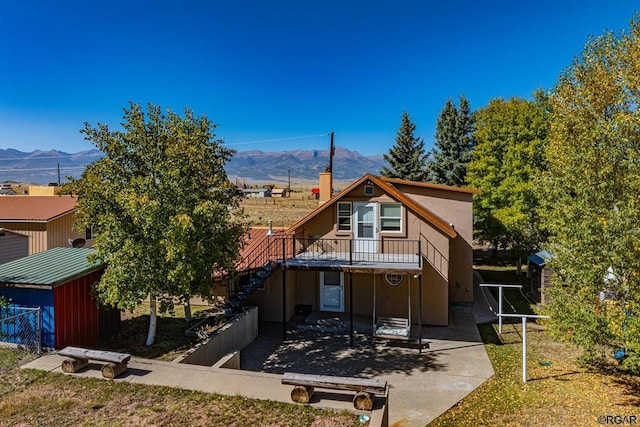 rear view of house featuring a mountain view, a patio area, and a lawn