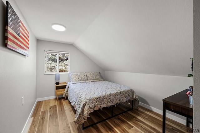 bedroom featuring vaulted ceiling and wood-type flooring