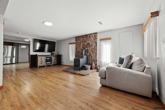 living room with light hardwood / wood-style floors and a wood stove