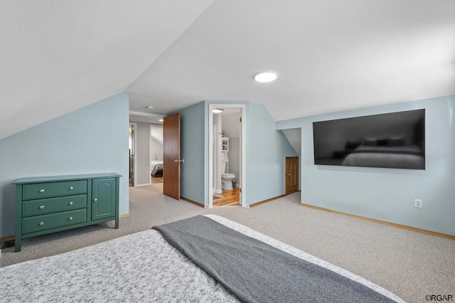 carpeted bedroom with ensuite bathroom and vaulted ceiling