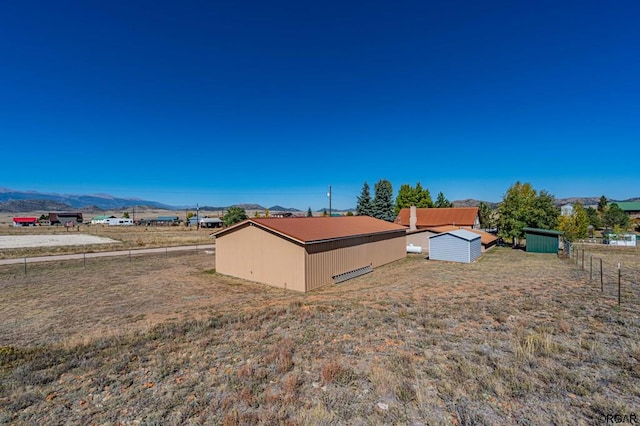 view of yard featuring a shed, a mountain view, and a rural view