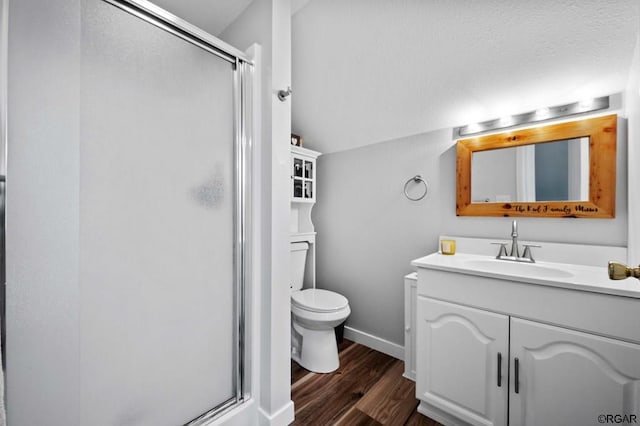 bathroom with lofted ceiling, hardwood / wood-style flooring, vanity, toilet, and a shower with door