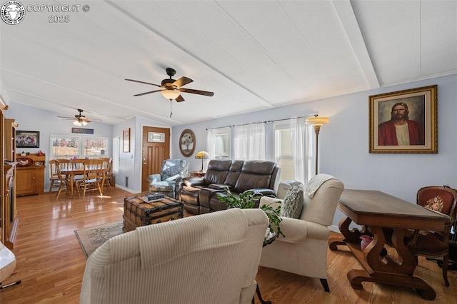 living room with lofted ceiling, ceiling fan, and light wood-type flooring