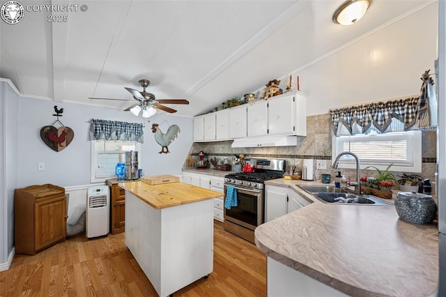 kitchen featuring sink, decorative backsplash, white cabinets, gas range, and light wood-type flooring