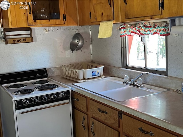 kitchen with brown cabinetry, white electric stove, light countertops, and a sink