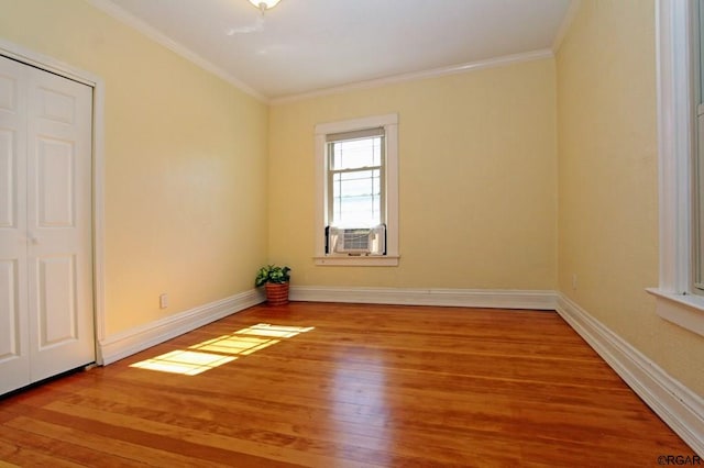 unfurnished room featuring cooling unit, hardwood / wood-style floors, and ornamental molding