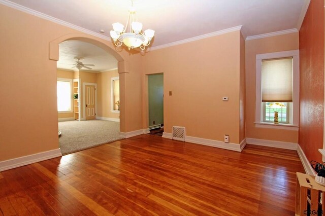 empty room featuring crown molding, a healthy amount of sunlight, ceiling fan with notable chandelier, and hardwood / wood-style flooring