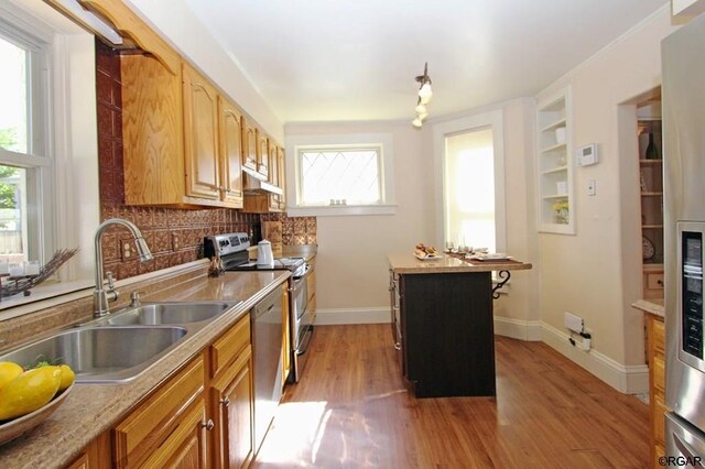 kitchen featuring sink, light hardwood / wood-style flooring, built in features, stainless steel appliances, and a kitchen island