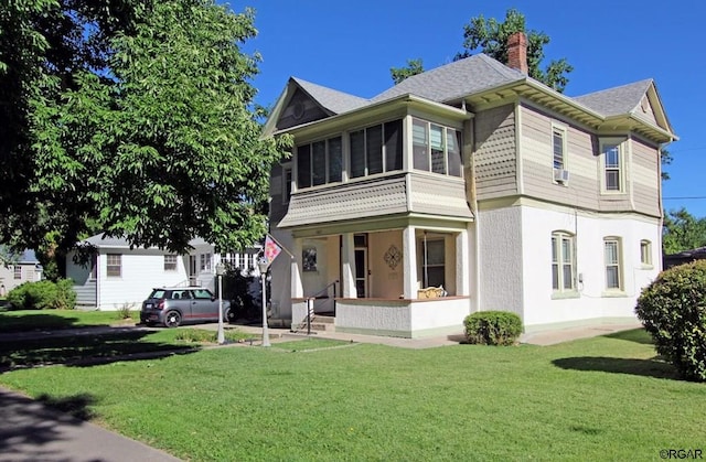 view of front of house featuring a sunroom, covered porch, and a front yard