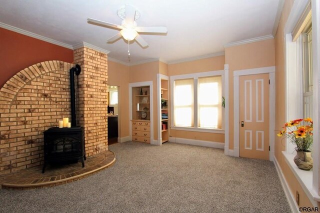 unfurnished living room featuring ornamental molding, a wood stove, and light colored carpet