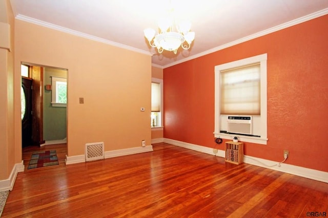 empty room featuring cooling unit, a notable chandelier, hardwood / wood-style flooring, and ornamental molding