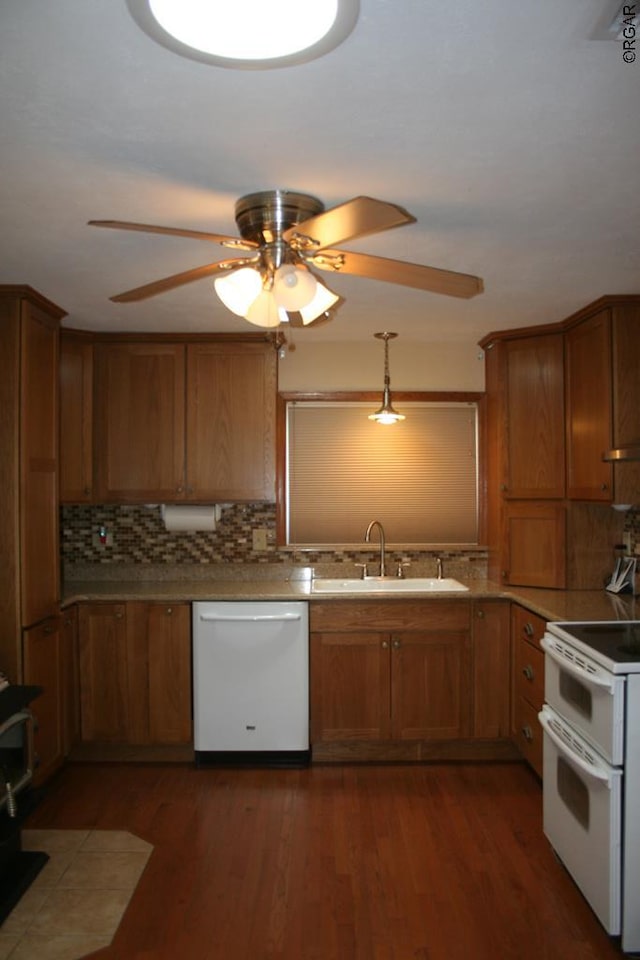 kitchen with sink, tasteful backsplash, decorative light fixtures, dark hardwood / wood-style flooring, and white appliances