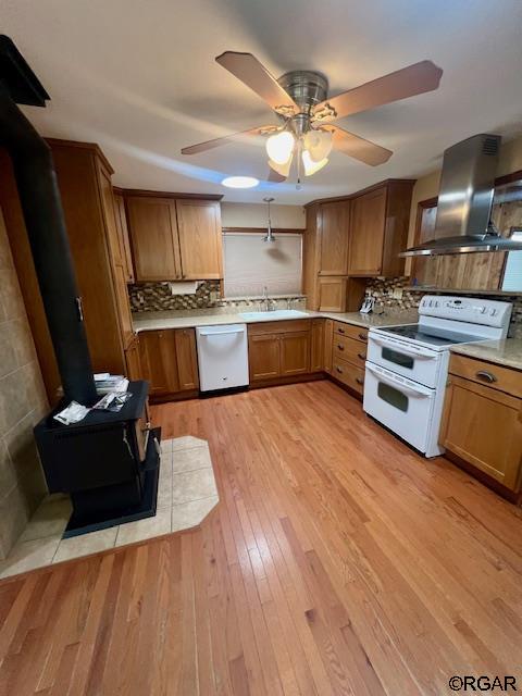 kitchen with island range hood, dishwasher, a wood stove, double oven range, and light wood-type flooring