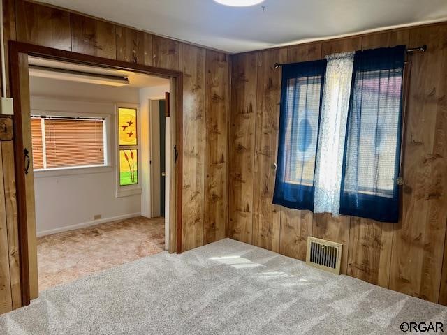 unfurnished bedroom featuring carpet and wood walls