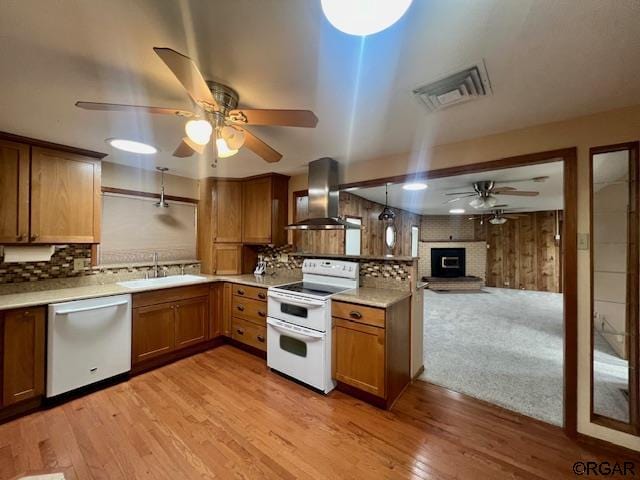 kitchen featuring sink, decorative light fixtures, double oven range, dishwasher, and wall chimney range hood