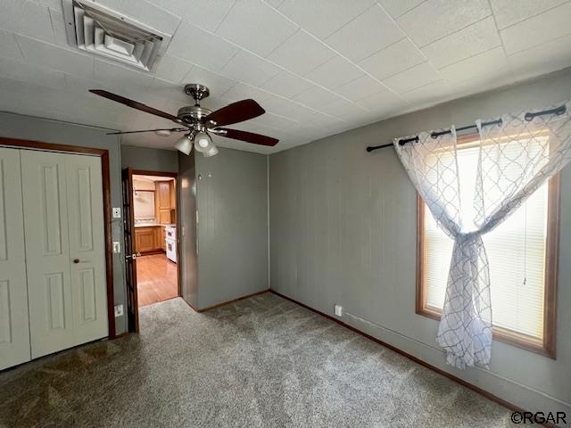 unfurnished bedroom with carpet, ceiling fan, and a closet