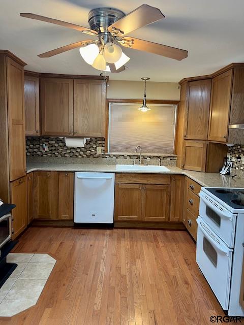 kitchen featuring tasteful backsplash, white appliances, sink, and light wood-type flooring