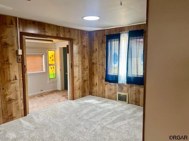 bedroom with multiple windows, carpet floors, and wood walls