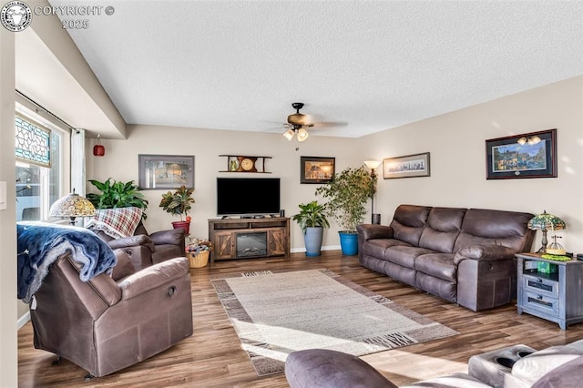 living room featuring ceiling fan, hardwood / wood-style floors, and a textured ceiling