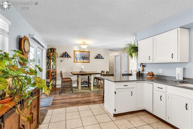 kitchen featuring white cabinetry, light tile patterned floors, a textured ceiling, and kitchen peninsula