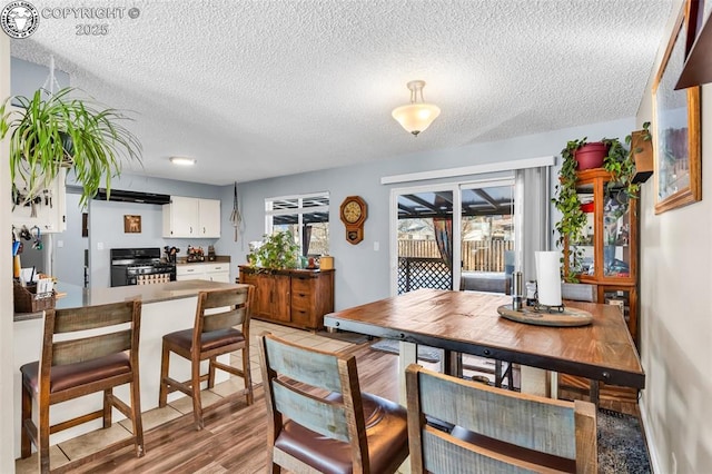 dining area with light hardwood / wood-style floors and a textured ceiling