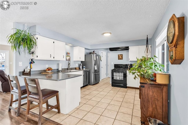 kitchen featuring sink, stainless steel appliances, white cabinets, a kitchen bar, and kitchen peninsula