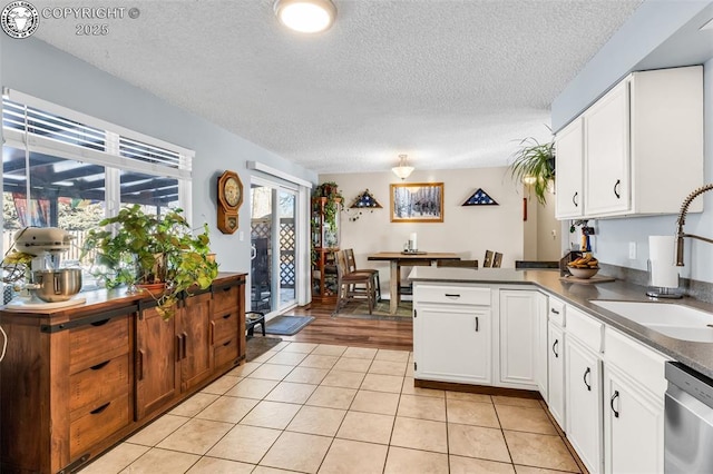 kitchen with white cabinetry, sink, stainless steel dishwasher, and light tile patterned flooring