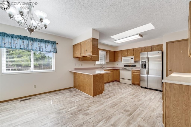 168 Willmoor Ct, Canon City, CO 81212 - kitchen featuring white appliances, a peninsula, light wood-style floors, light countertops, and a textured ceiling