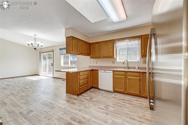 168 Willmoor Ct, Canon City, CO 81212 - kitchen featuring stainless steel fridge, white dishwasher, a peninsula, a textured ceiling, and a chandelier