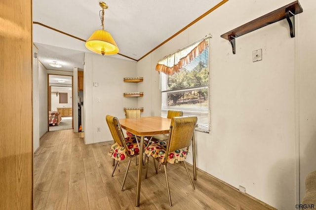 dining space with crown molding and light hardwood / wood-style flooring