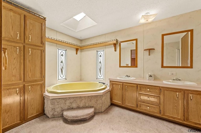 bathroom featuring vanity, a bathtub, a textured ceiling, and a skylight