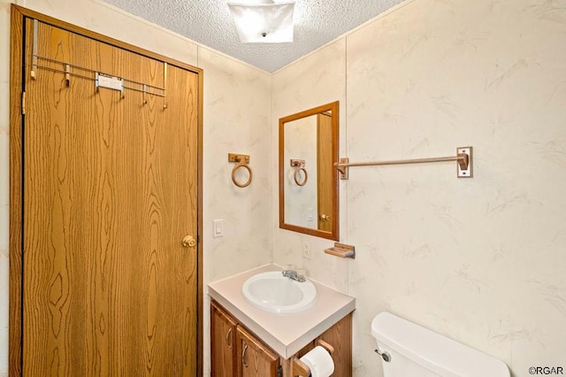 bathroom with vanity, toilet, and a textured ceiling